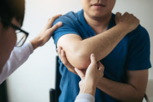 A doctor is checking man's elbow